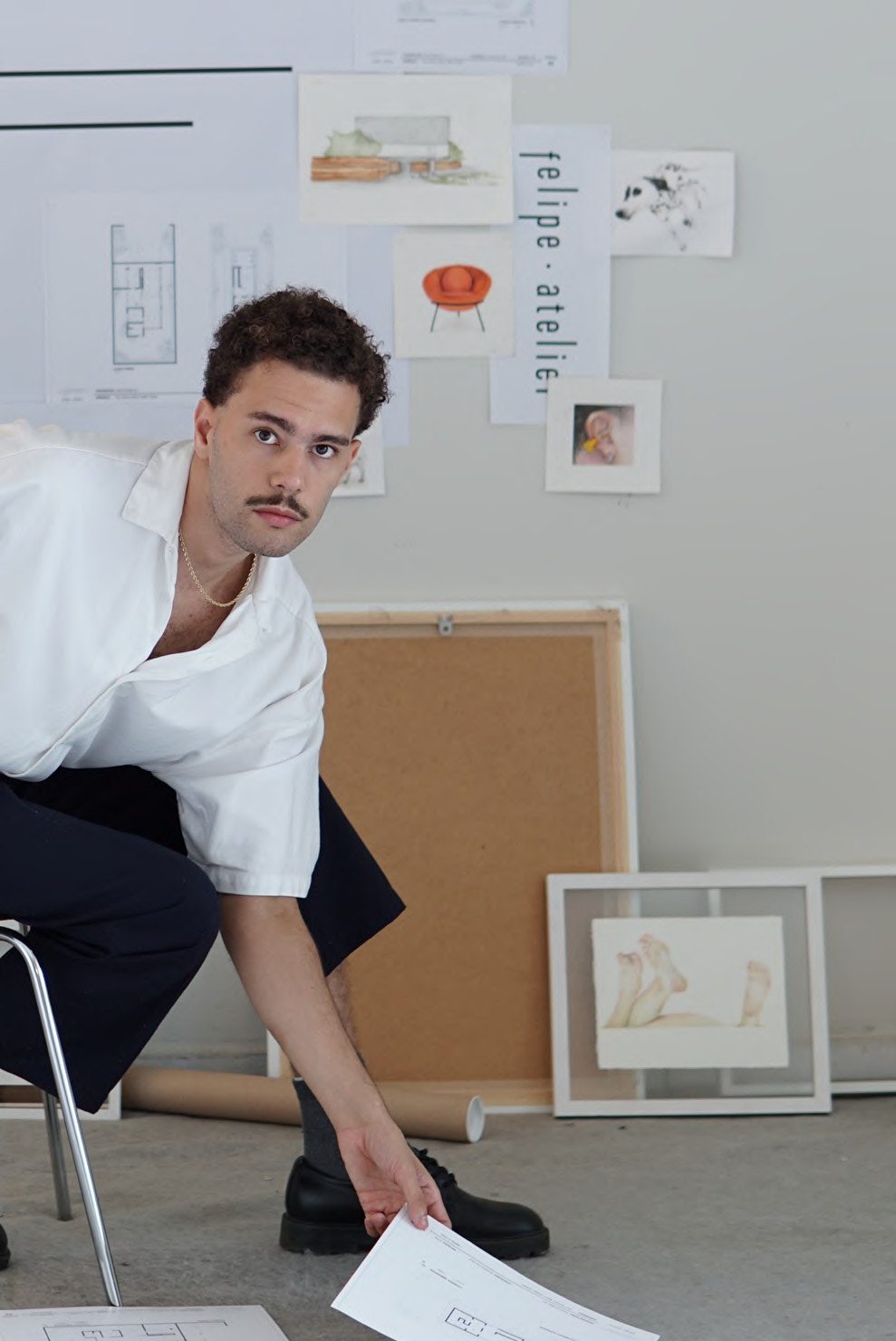 Felipe Sousa em seu ateliê, cercado de croquis e referências